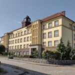 Historická budova základní školy v Novém Boru s hodinovou věží a žlutou fasádou
