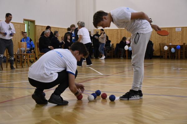 Dva chlapci připravují míčky při hře boccia v tělocvičně. Fotografie zachycuje spolupráci, soustředění a inkluzivní radost ze sportu v rámci projektu Ekvilibro.